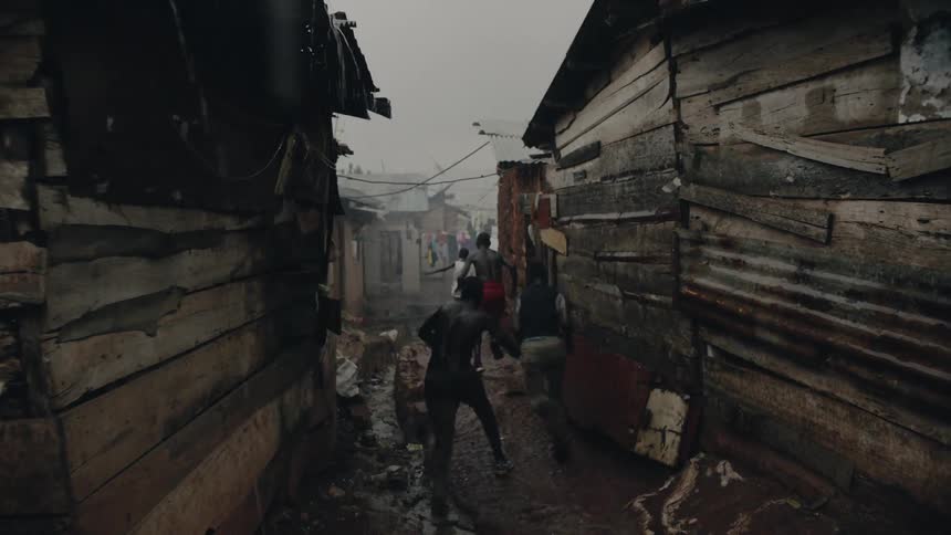 Teenagers run by buildings in the rain