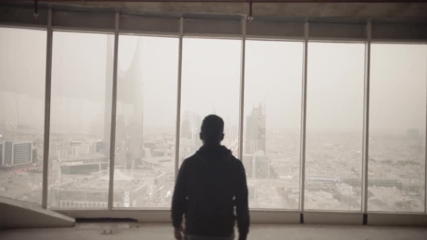 A man walks toward the windows on an unfinished floor of a tall building