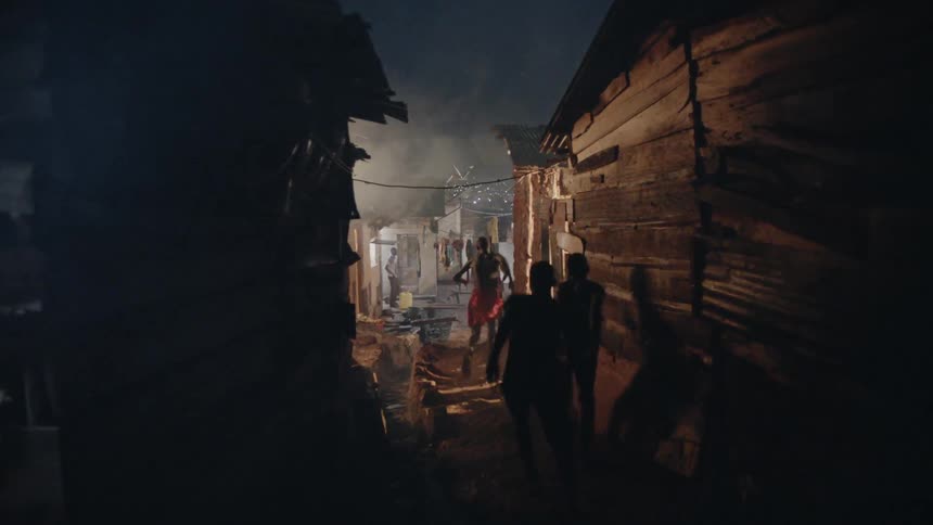 Three boys chase a smaller boy through a village at night