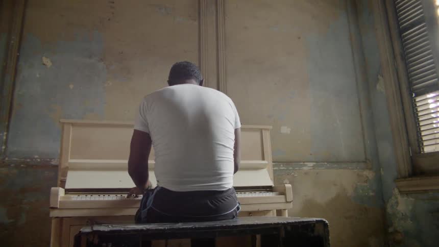 Man sits on a bench as he plays a piano