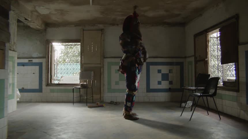 Costumed man dances with props indoors