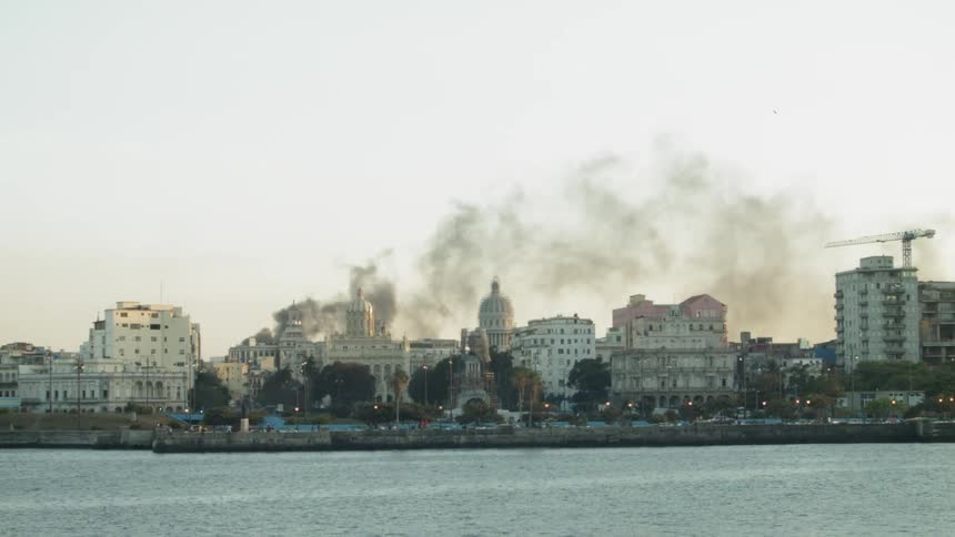 Smoke pours out of the city as vehicles travel
