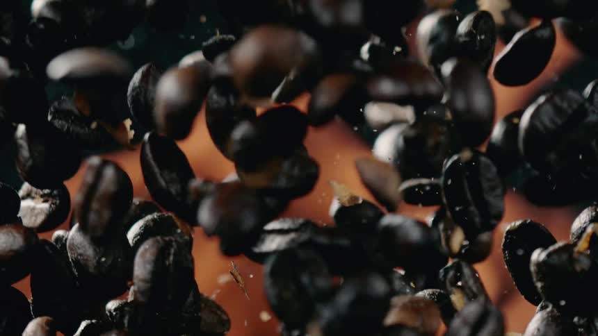 Coffee beans are flinging in the air by flames and being roasted