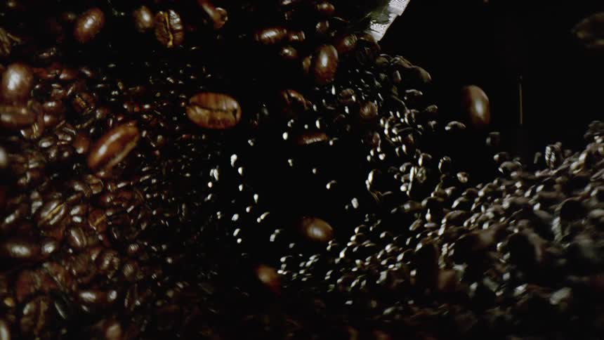 Coffee beans falling in a swirling pattern against darkness