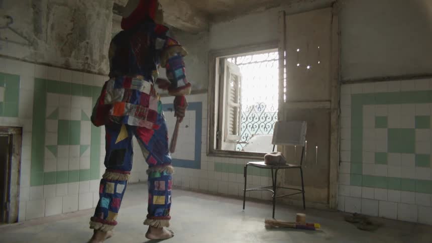 Person wearing a costume dances in an empty room