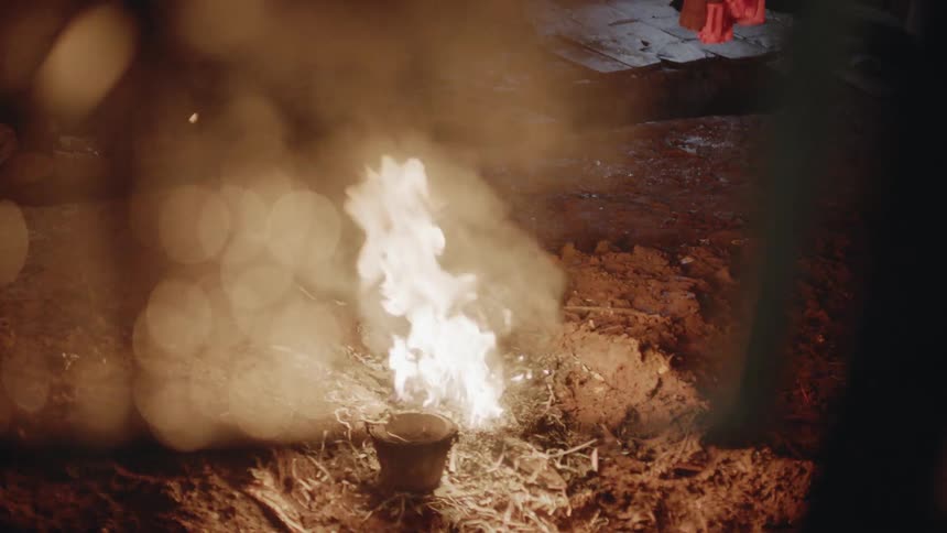 A fire burns outside on the ground at night