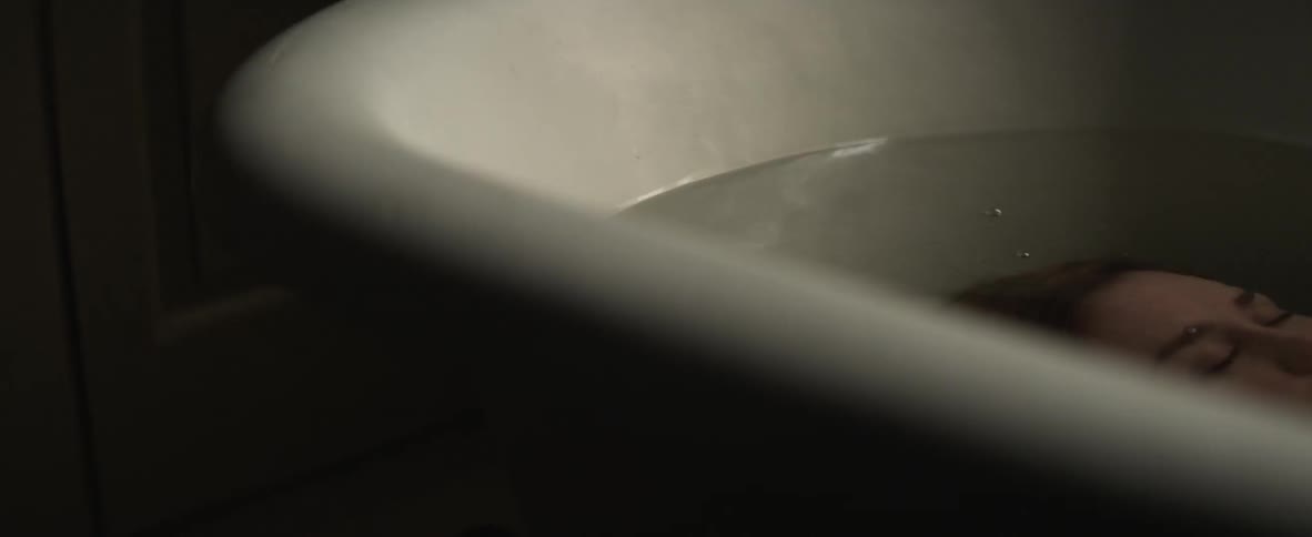 Someone in a bathtub lowers their head below the water line