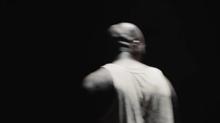 A man turns around in a circle in a dark room
