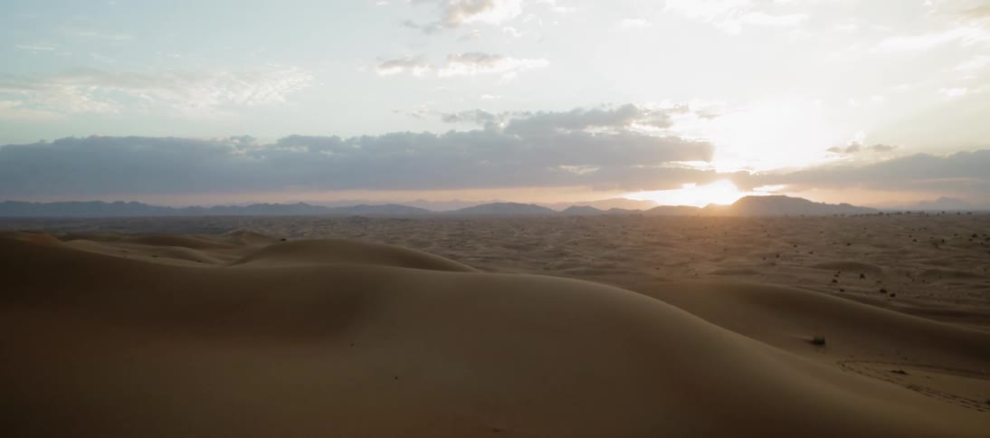 The sun sets over a desert landscape