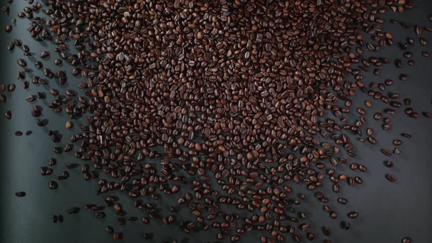 Coffee beans are rolling down a surface