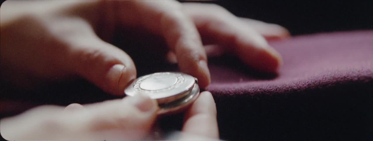 Person closes a locket necklace that contains a pill