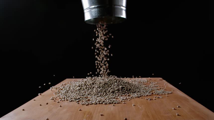 The coffee beans fall through the funnel onto the table