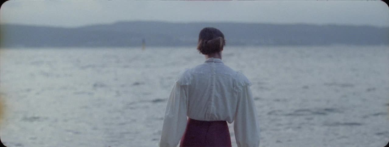A woman walks out into the water of the shore