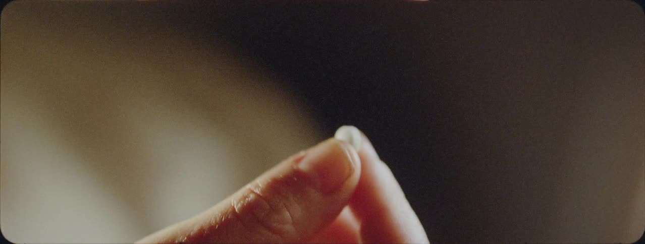 Person holding a pill in their fingertips