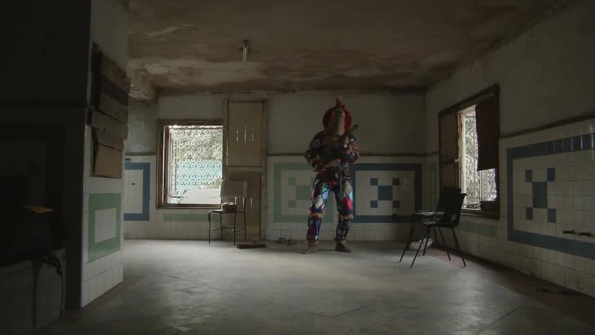 Person wearing scarecrow mask and costume is dancing in house