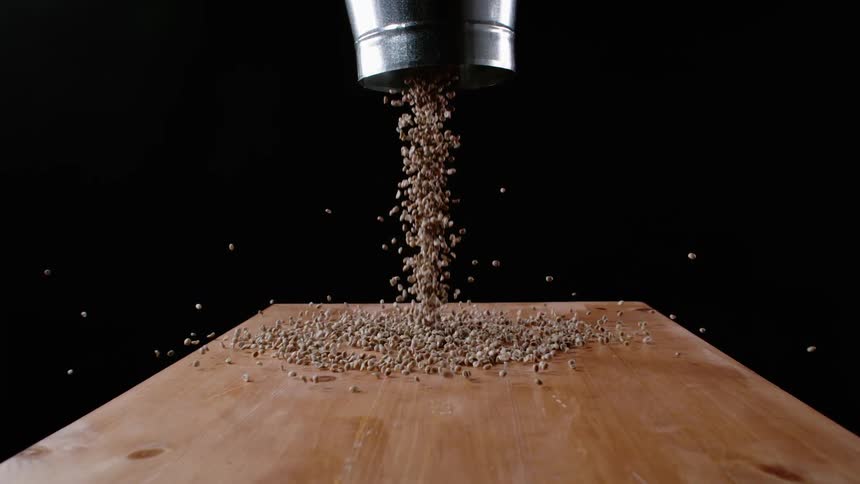 Coffee beans spill from a bucket onto a table and spill off the table