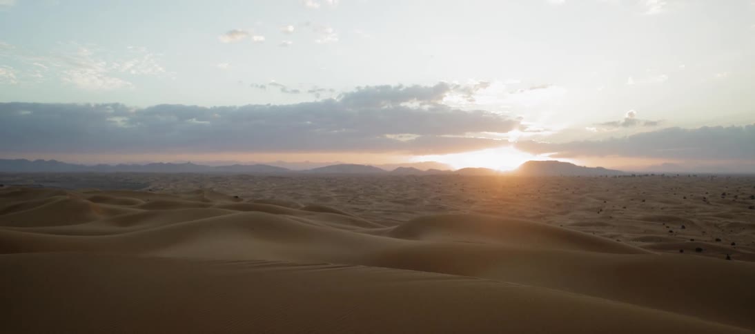 The sun sets over a desert landscape