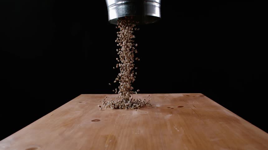 The dark coffee beans are poured on the table