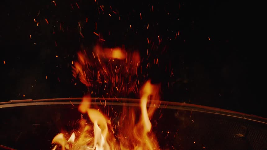 Fire burns and sparks outside at night