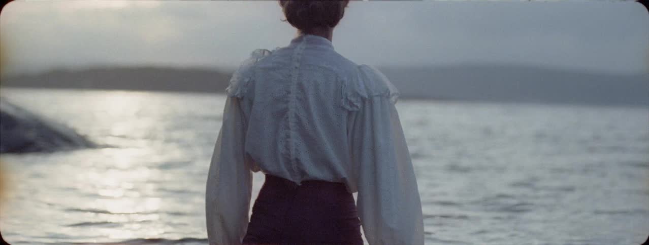 Woman wearing a shirt and skirt wades in a lake