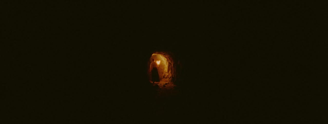 The tunnel is lit at the end by a torch someone is carrying