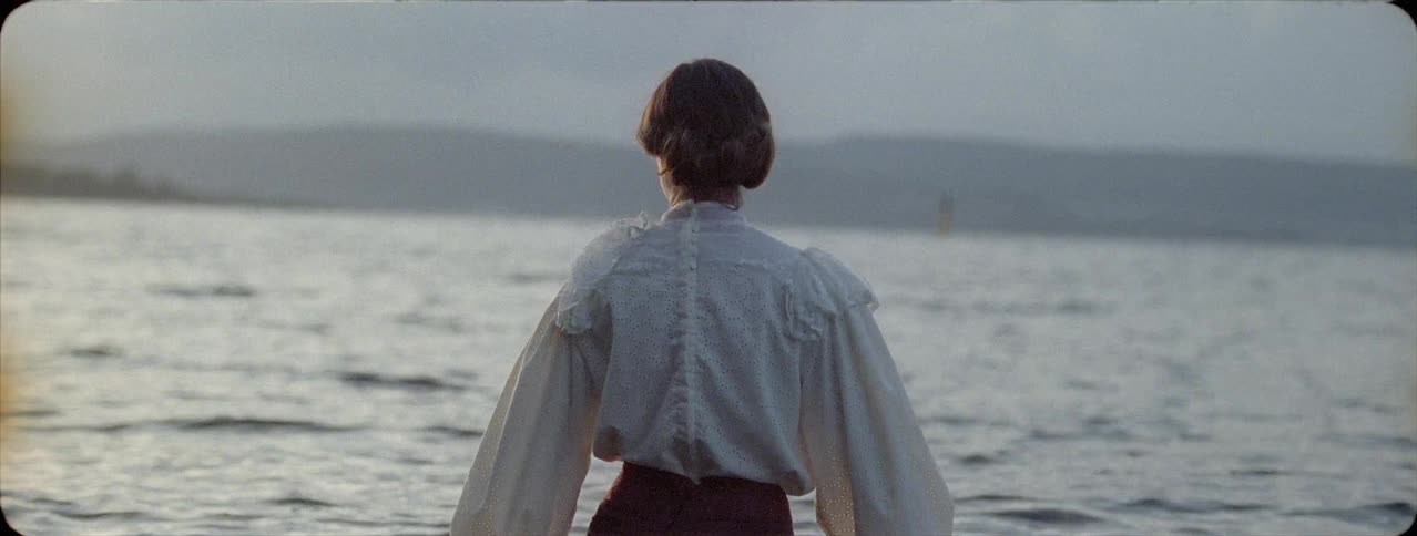 A woman stands by the water taking in the view
