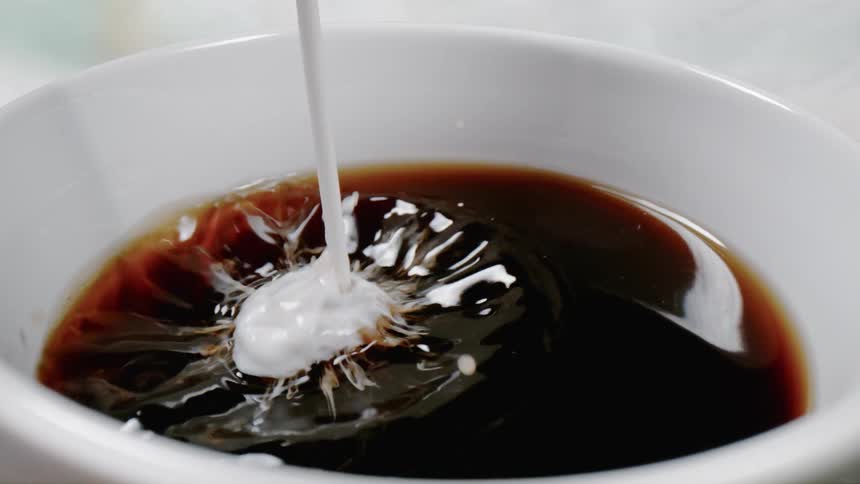 Creamer is poured into a cup of coffee