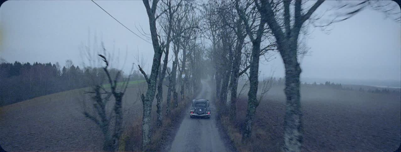 An antique car is driven on a rural road