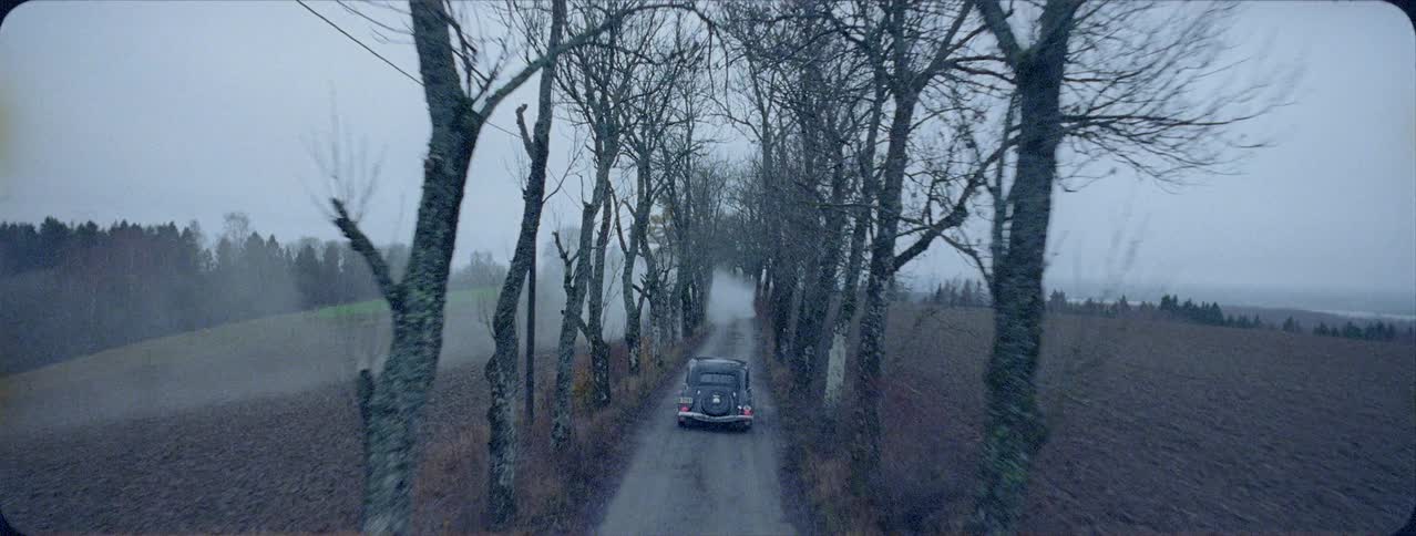 An antique car is driven on a rural road