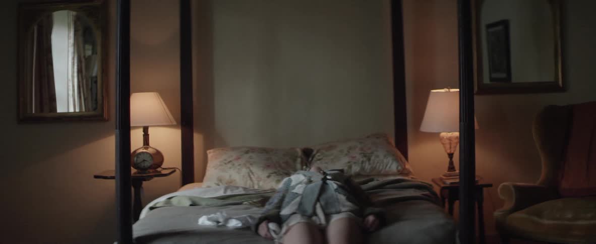 Woman sitting on a bed falls back