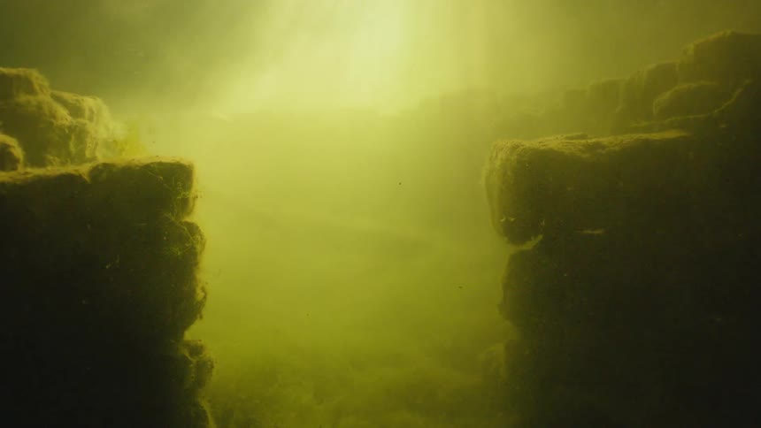 The water is murky by the rocks underwater