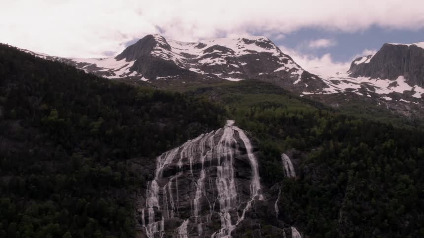 The snow covered mountain has a waterfall at the top