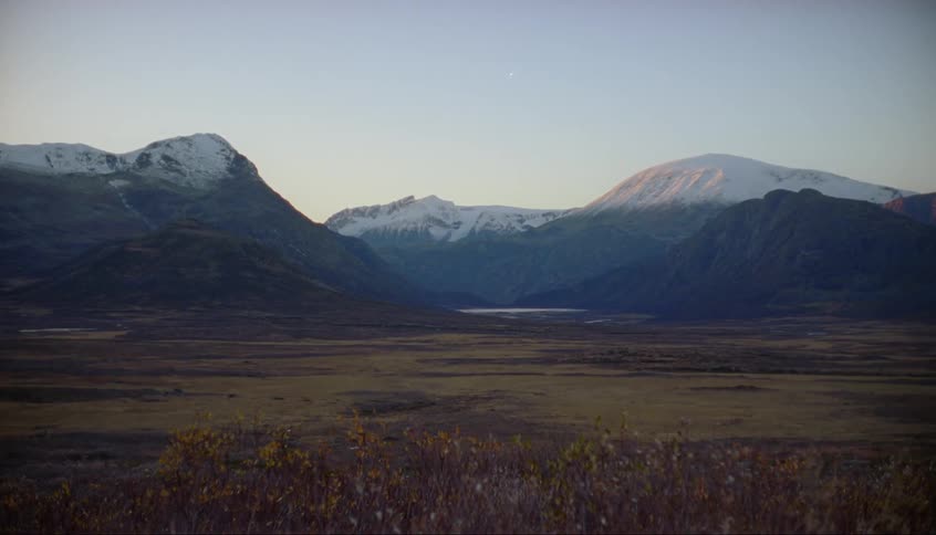 Dawn is breaking over a snow-tipped mountain range