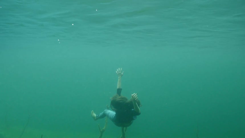 A woman attempts to swim towards the surface of the water