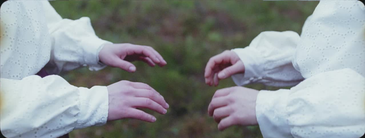 Hands of two women reach across and toward each other then mirror movement