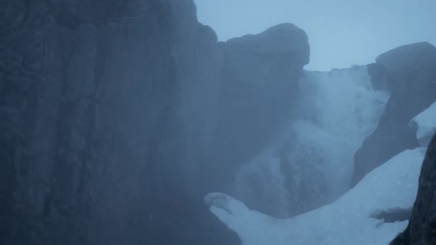 Water splashes off a cliff on a foggy day