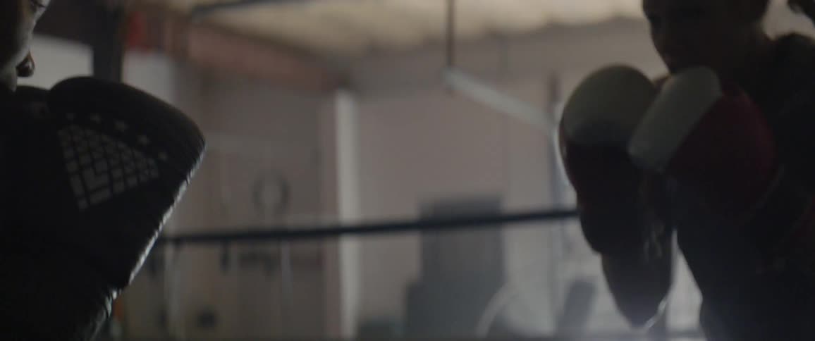 Two people are boxing in the dark ring
