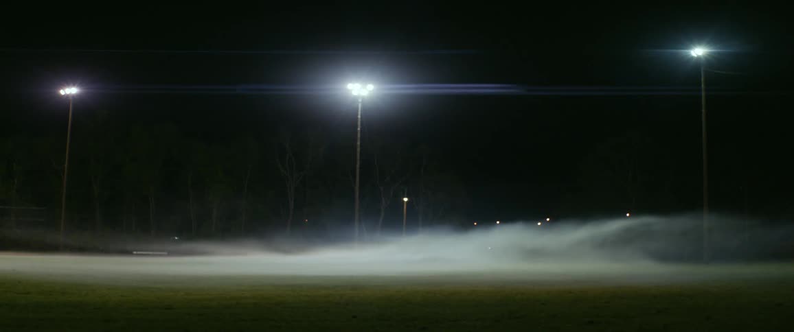 The lamp post lights up on the foggy field