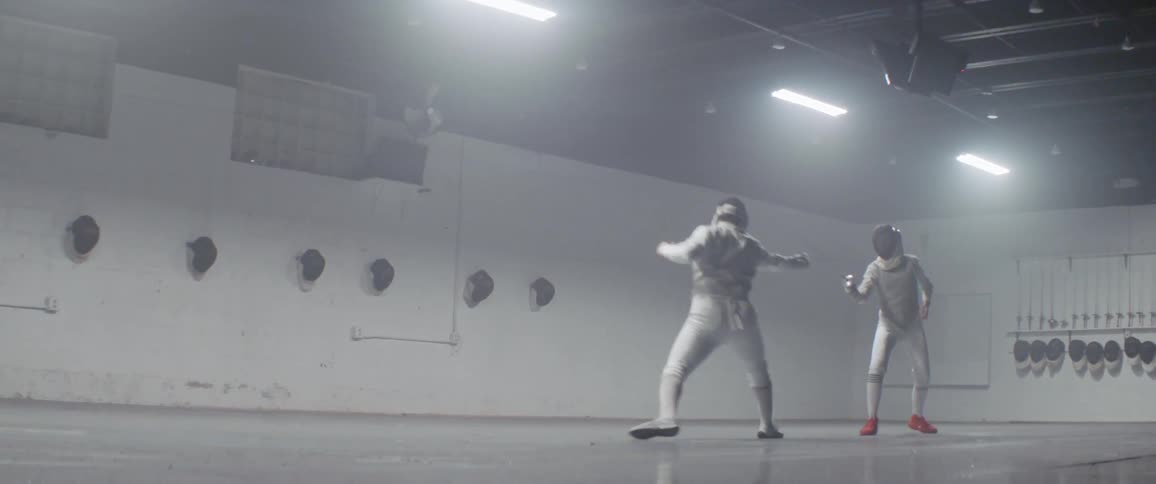 Two people fencing in a gymnasium