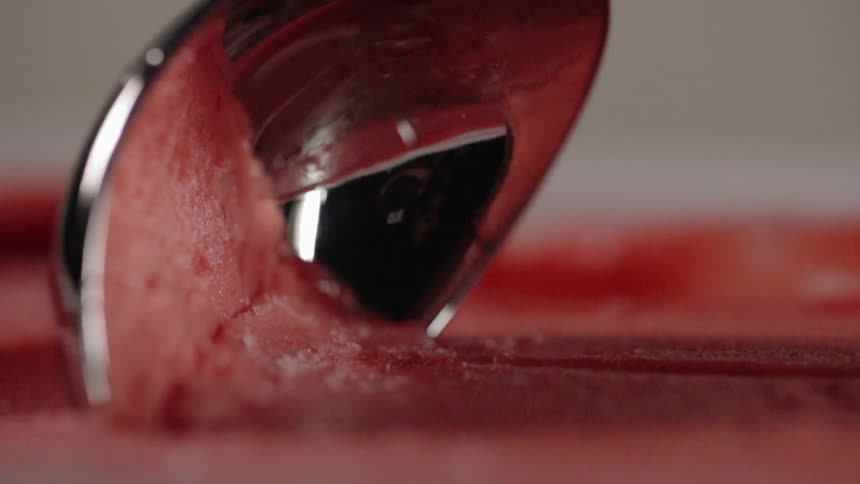 A stainless steel scooper scoops out ice cream