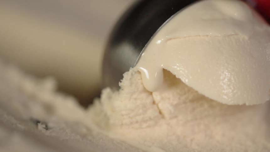 Ice cream scoop scoops a white ball of ice cream