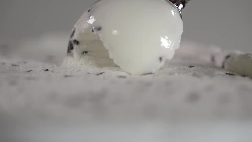 Ice cream scoop scoops a white ball of ice cream