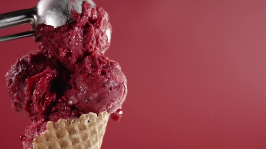 Ice cream scoop puts a scoop of red ice cream on a cone
