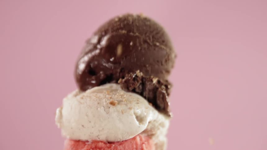 Toffee flakes are falling over ice-cream scoops in a cone