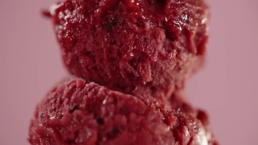 Ice cream scoop puts a scoop of red ice cream on top of another scoop of ice cream
