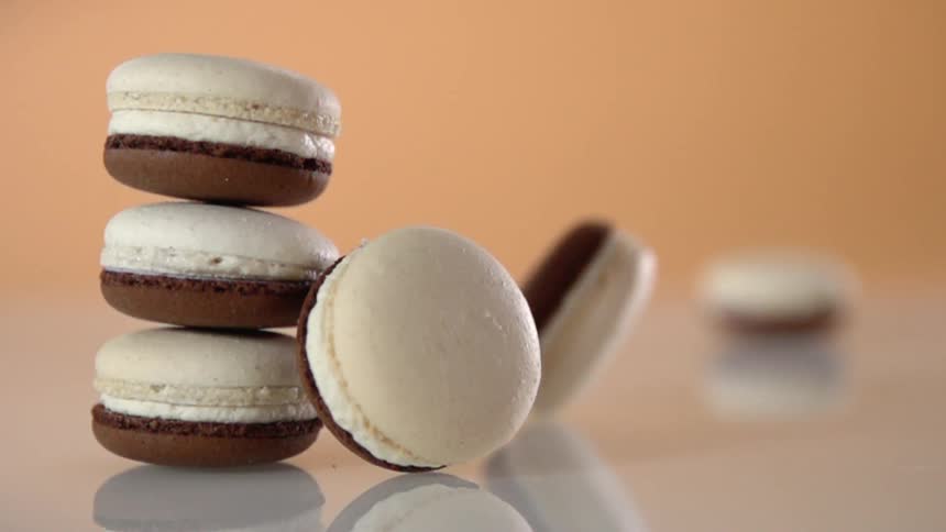 A macaroon slides across a surface past a stack of macaroons