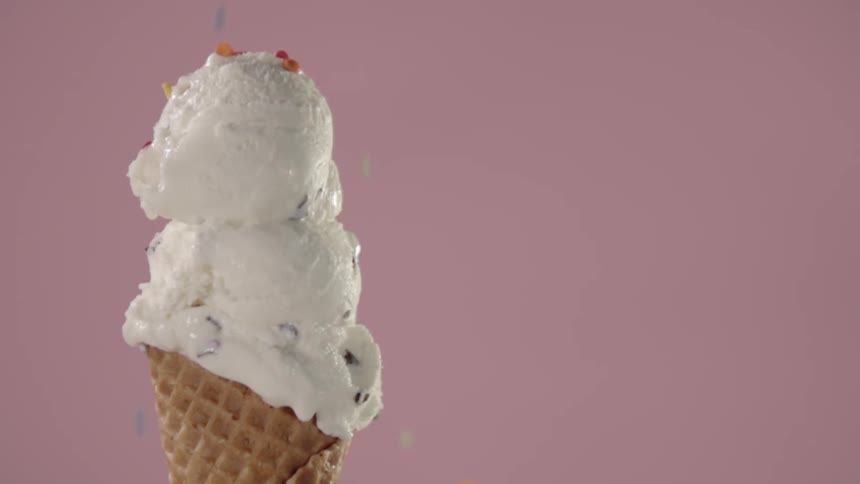Sprinkles fall onto an ice cream cone
