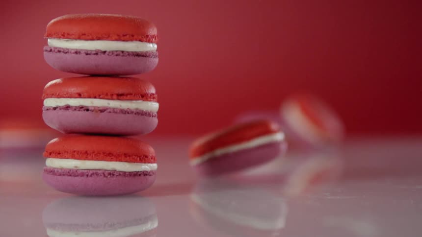 Stack of red and purple macaroons and one macaroon spins around next to the stack