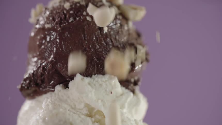 Chopped nuts are dropped on a double scoop of chocolate and vanilla