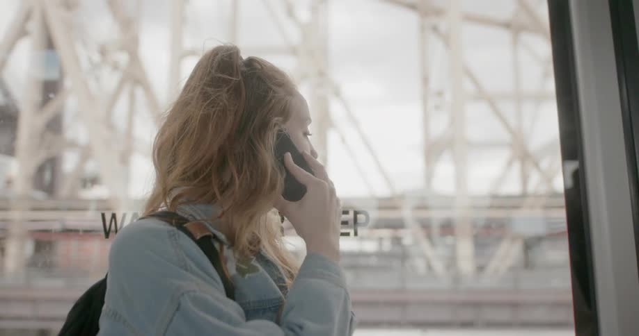 A woman is talking on the phone by the window